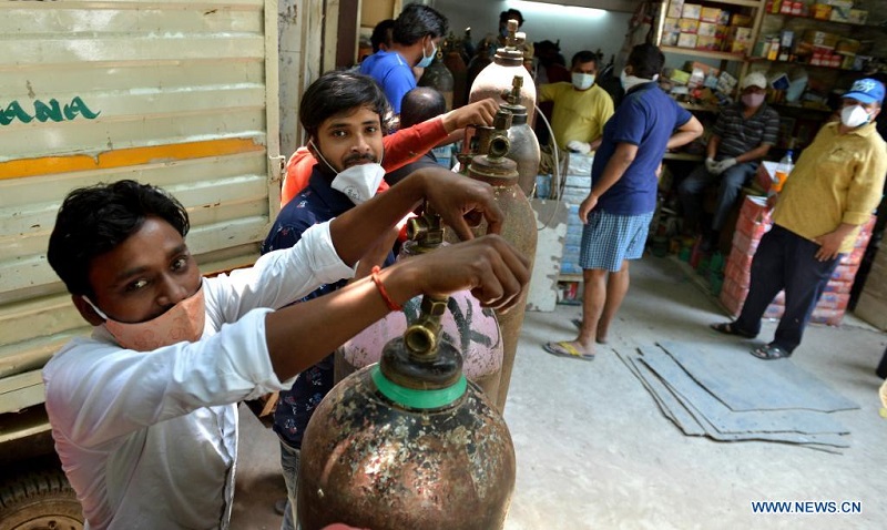 People wait to refill oxygen cylinders for COVID-19 patients in India